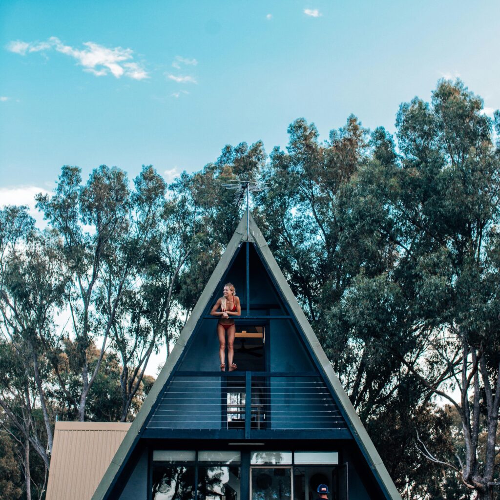 A modern A-frame cabin with a blue facade and people enjoying the outdoors.