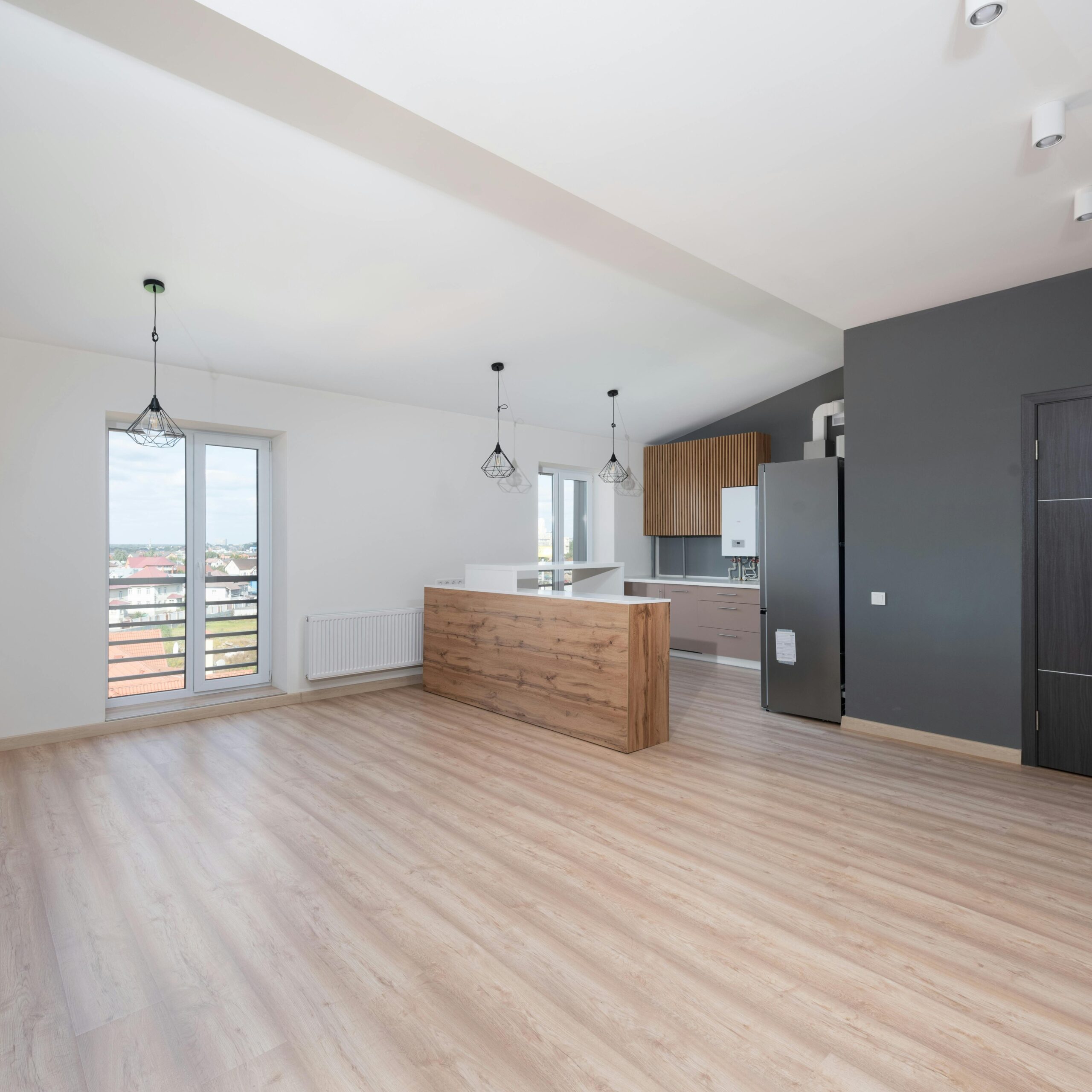 Spacious, bright, and empty open-plan kitchen and living area with wooden flooring.